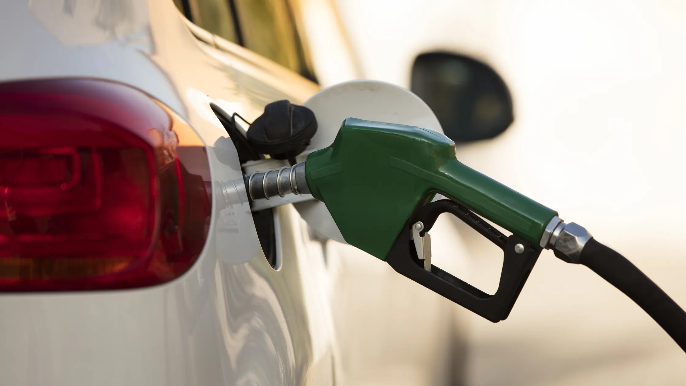 pistola-de-gasolina-verde-conectada-al-tanque-de-combustible-de-un-automovil-blanco